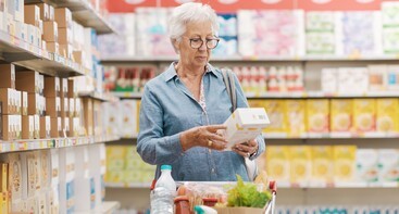 Vrouw bekijkt voedingslabel in supermarkt